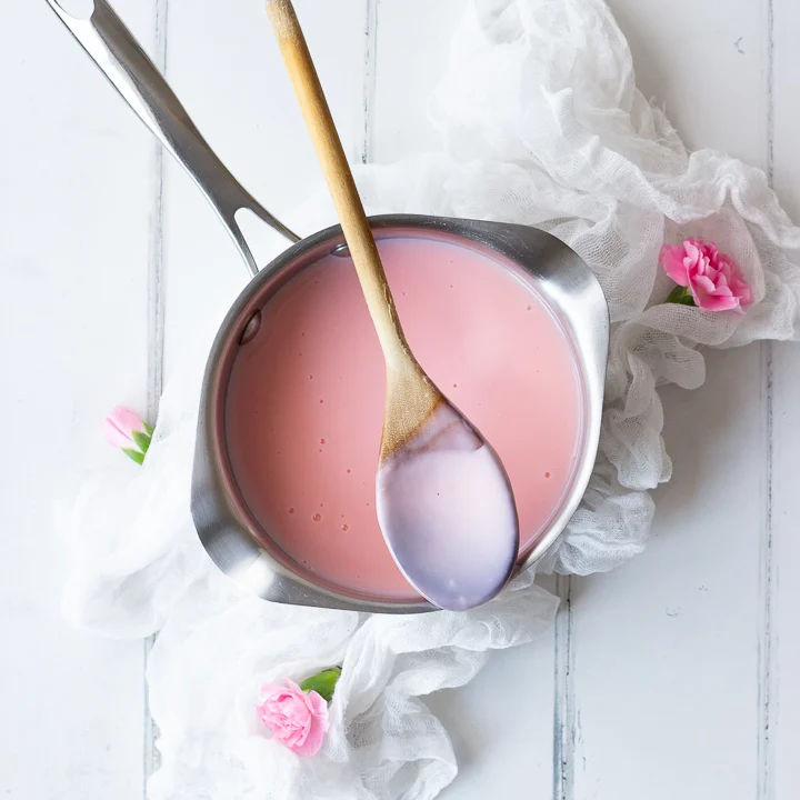 pink custard in a saucepan with a spoon