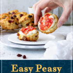 Someone picking up a fruit scone with jam and clotted cream on it. A text overlay says 'Easy peasy fruit scones'