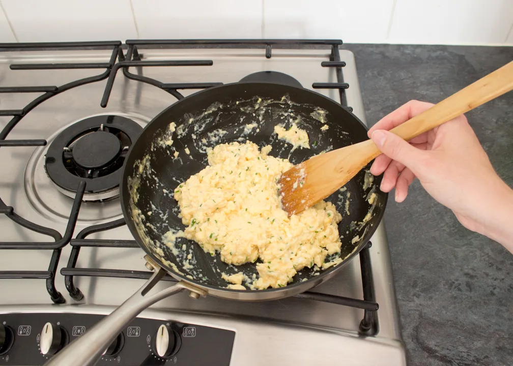 Cheese and chive scrambled egg croissants in a frying pan.