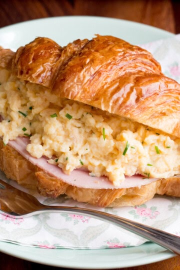 A croissant filled with ham and cheese and chive scrambled eggs.