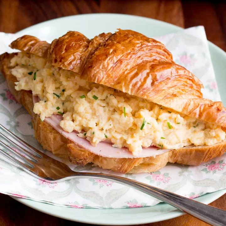 A croissant filled with ham and cheese and chive scrambled eggs.
