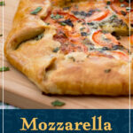 A whole tomato galette on a chopping board topped with fresh basil. A text overlay says 'Mozzarella tomato galette'.