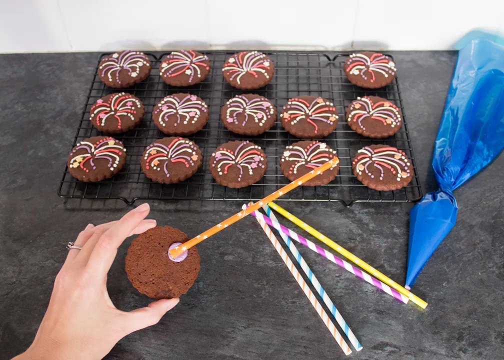 Straws being stuck onto the back of firework biscuits with icing.