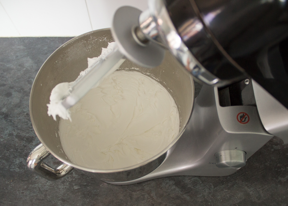Egg whites, icing sugar and lemon juice being whipped together in an electric stand mixer.