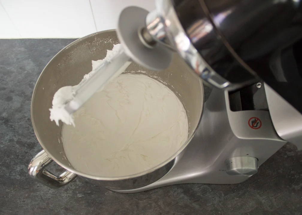 Egg whites, icing sugar and lemon juice being whipped together in an electric stand mixer.