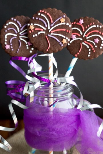 Three firework biscuits in a jar wrapped in colourful curling ribbon.