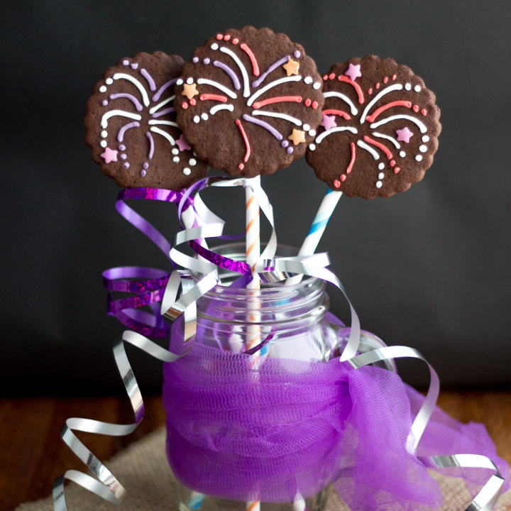 Three firework biscuits in a jar wrapped in colourful curling ribbon.
