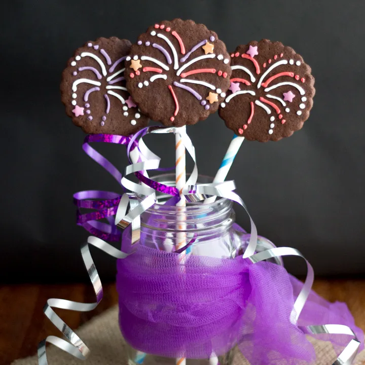 Three firework biscuits in a jar wrapped in colourful curling ribbon.