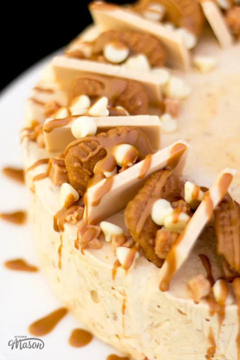 Melted Biscoff drizzled over a showstopping Biscoff ice cream cake on a large white plate.