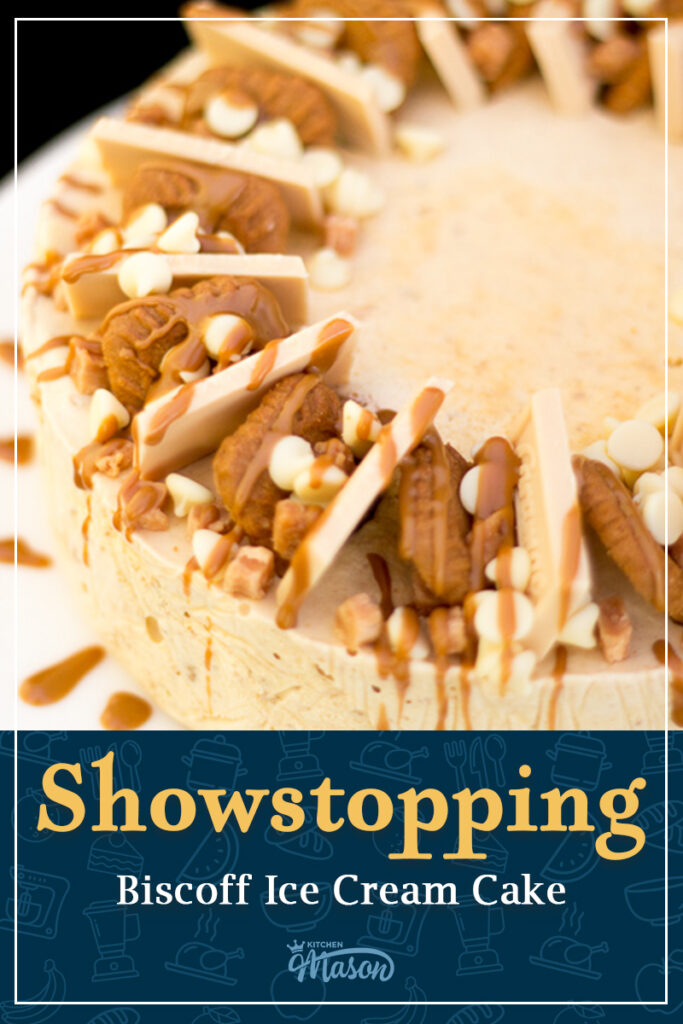 A Biscoff ice cream cake on a white plate. The top has been decorated with Biscoff biscuits, blond chocolate, white chocolate chips, fudge pieces, and melted Biscoff spread. A text overlay says "Showstopping Biscoff Ice Cream Cake".