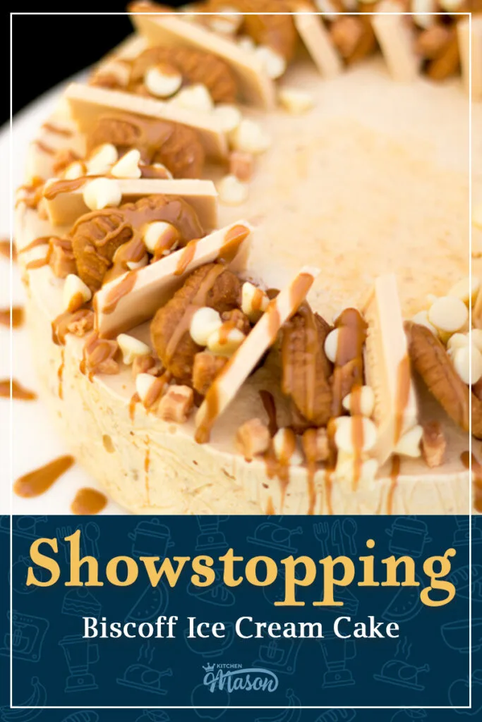 A Biscoff ice cream cake on a white plate. The top has been decorated with Biscoff biscuits, blond chocolate, white chocolate chips, fudge pieces, and melted Biscoff spread. A text overlay says "Showstopping Biscoff Ice Cream Cake".