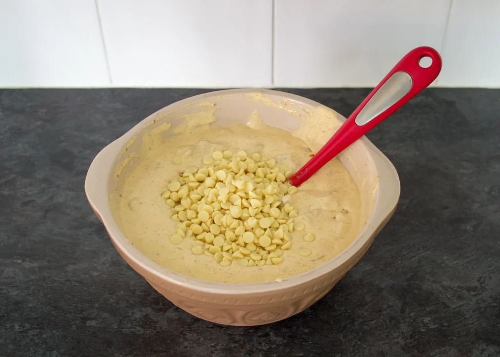 White chocolate chips being added to the base mixture of an ice cream cake.