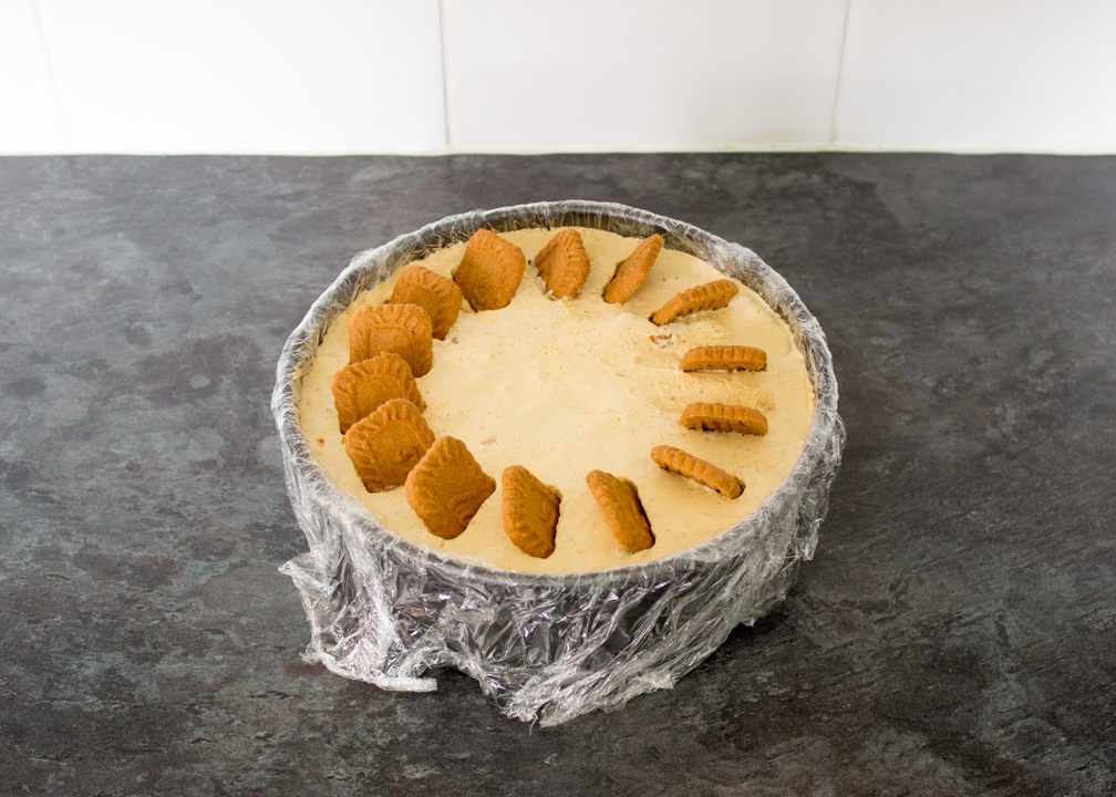 Biscoff biscuits pressed into the top of a partially set ice cream cake.