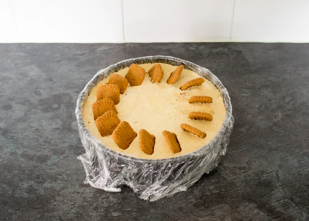 Biscoff biscuits pressed into the top of a partially set ice cream cake.