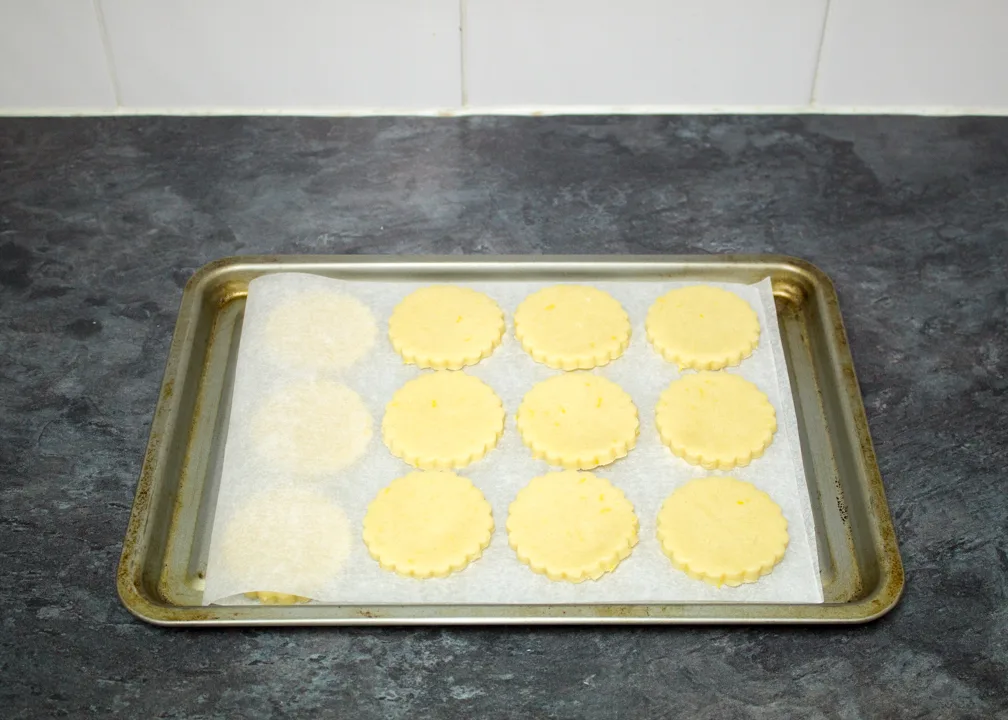 Cut out lemon biscuits on a lined baking tray ready to be chilled.