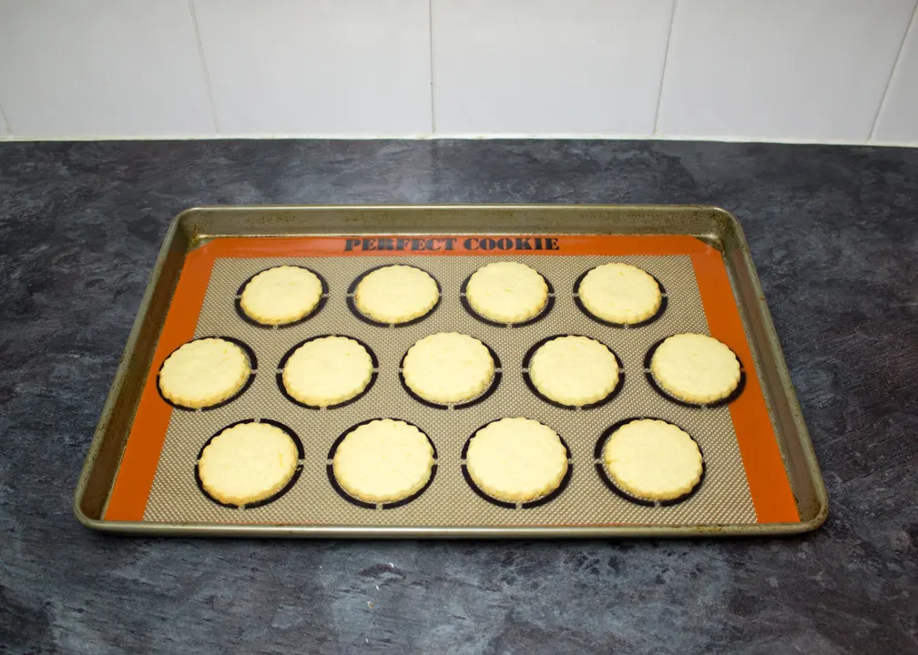 Baked lemon biscuits on a lined baking tray.