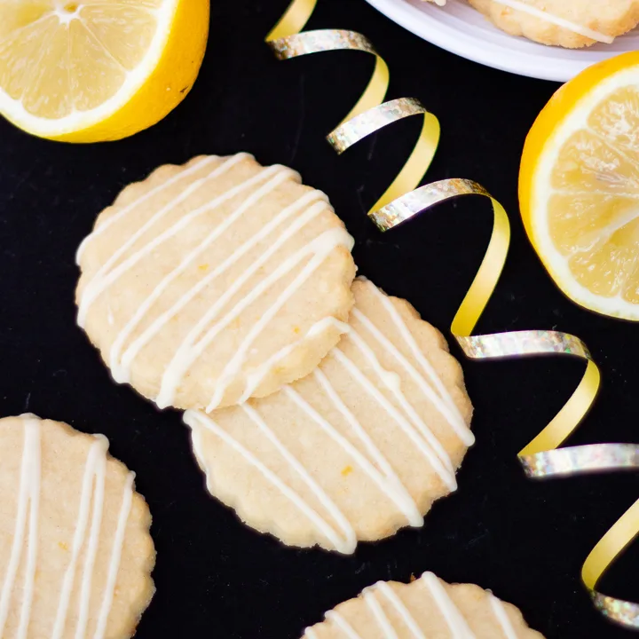 Lemon biscuits with gold curling ribbon and sliced lemons beside them.