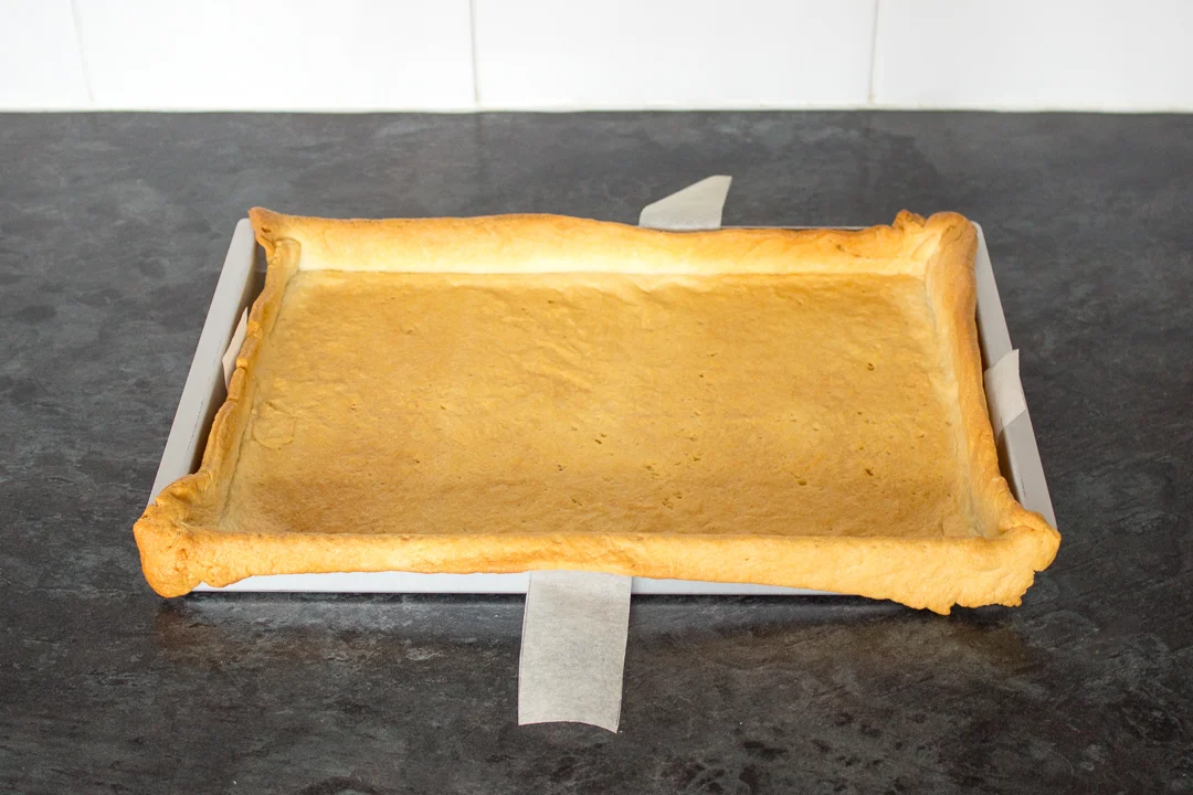 A baked shortcrust pastry case in a large rectangular baking tin.