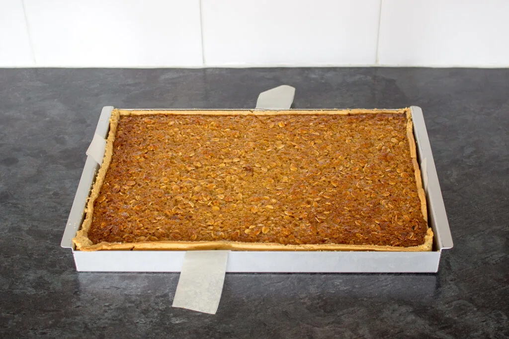 A fully baked treacle tart traybake in a rectangular baking tin.