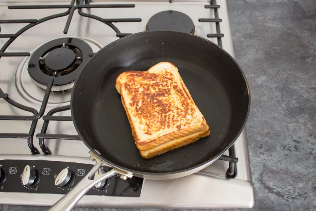 Nutella sandwiched between two slices of eggy bread in a frying pan.
