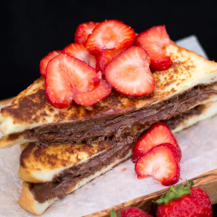 Strawberry Nutella French toast on a wooden board.