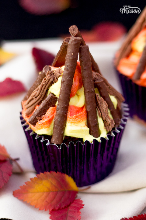 A bonfire cupcakes with red and orange leaves scattered around it.
