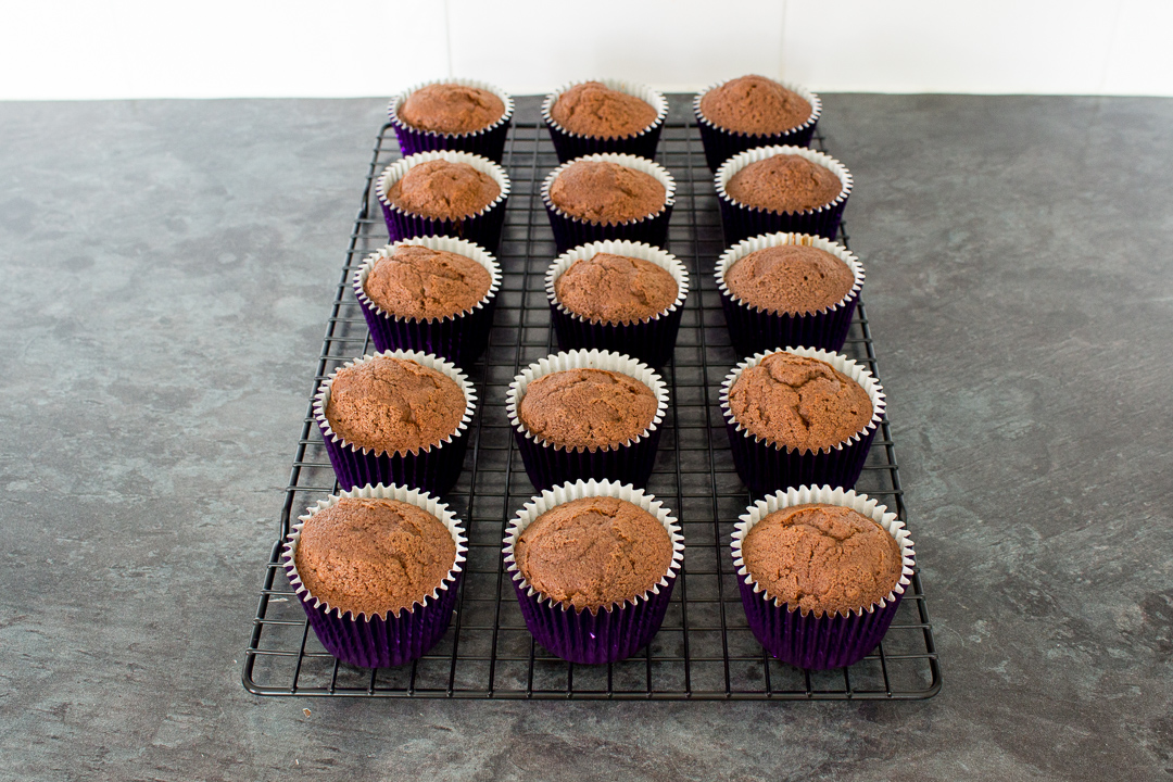 Baked chocolate cupcakes cooling on a wire rack.