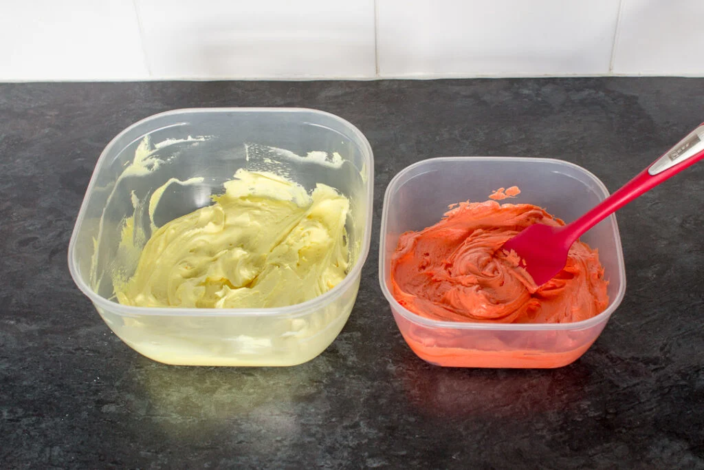 Orange and yellow buttercream frosting in two separate plastic tubs.