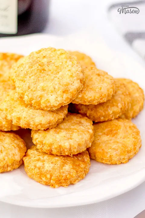 Lots of cheese biscuits on a small white plate.
