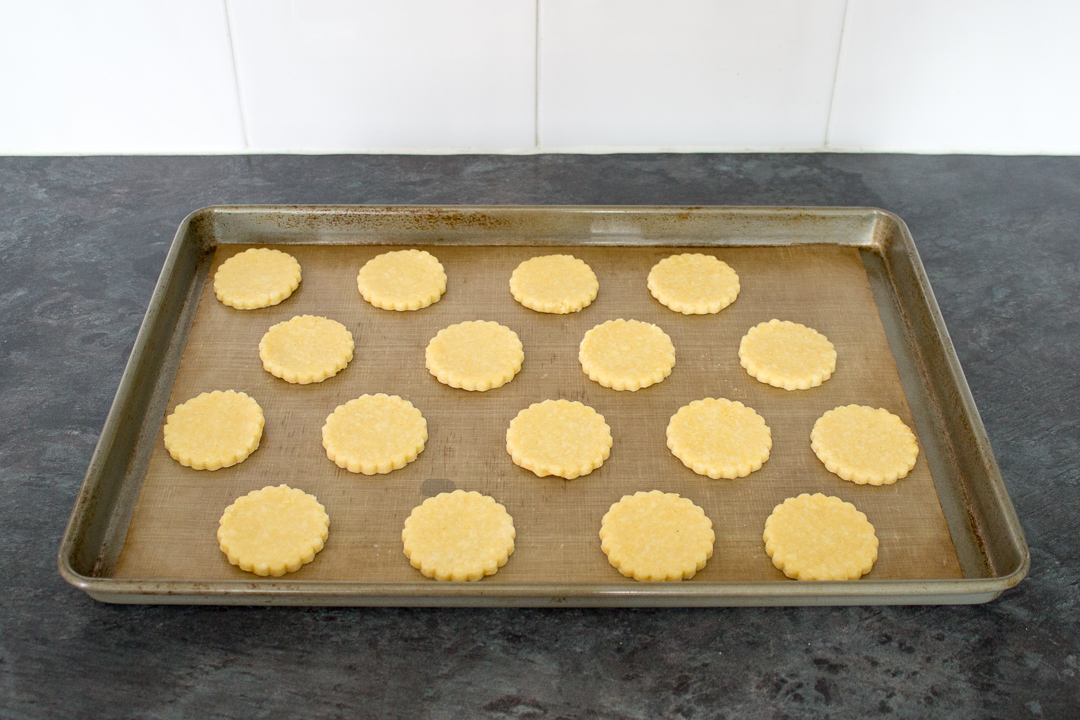 Unbaked cheese biscuits on a lined baking tray ready for the oven.