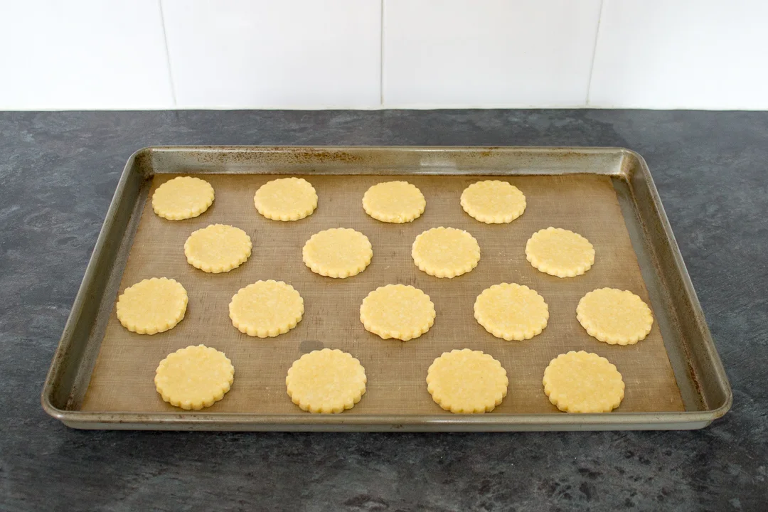 Unbaked cheese biscuits on a lined baking tray ready for the oven.