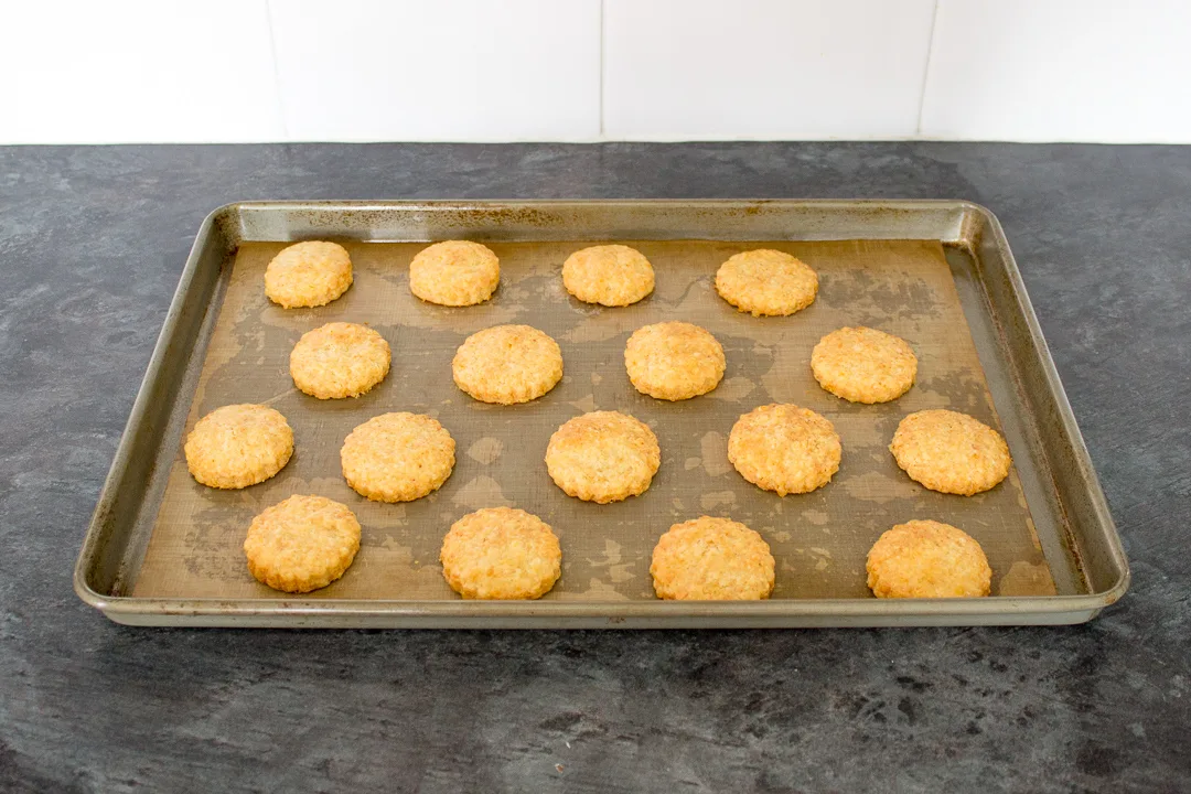 Baked cheese biscuits on a lined baking tray.