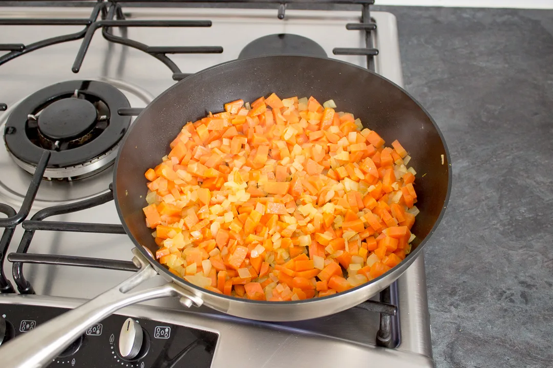 Root vegetables softening in a frying pan.