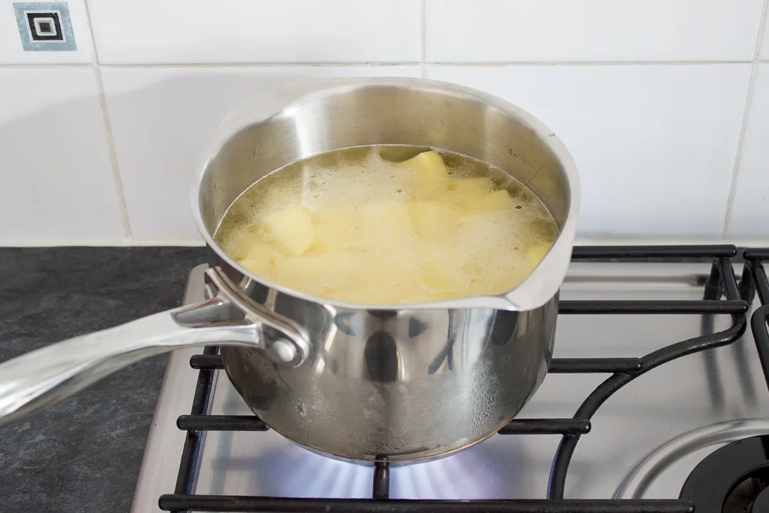 Potatoes coming to a boil in a large saucepan.