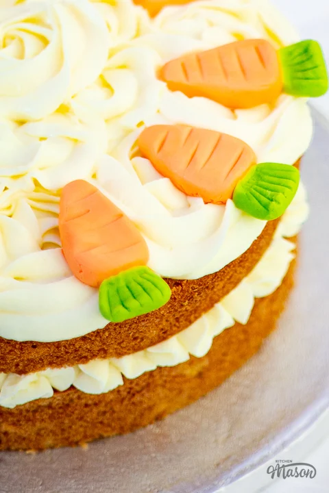 A two layer carrot cake decorated with cream cheese icing and homemade fondant carrots.