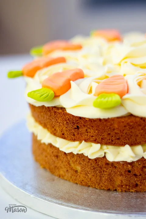 Side view of a two layer carrot cake sandwiched together and decorated with cream cheese icing.