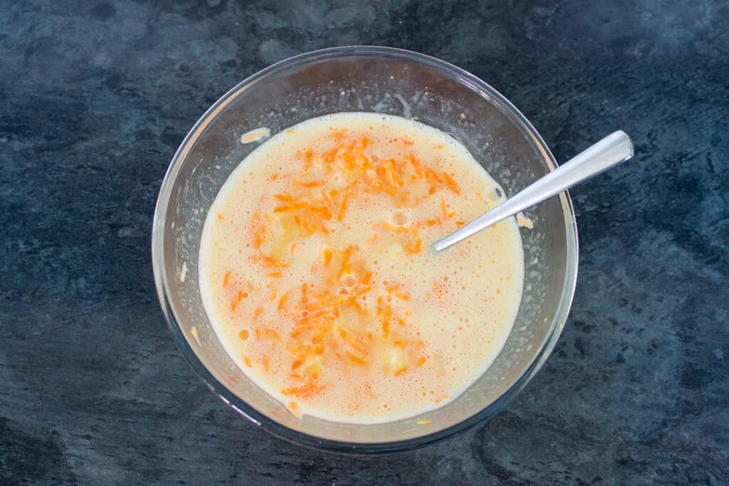 Fruits, zest, egg and oil in a mixing bowl with a fork.