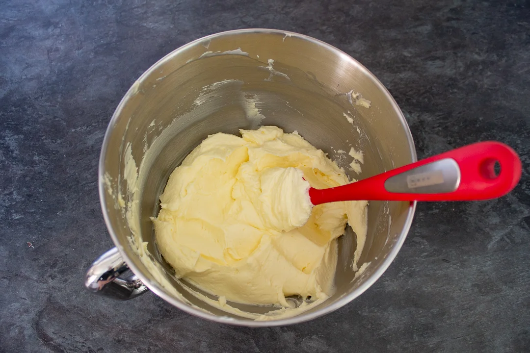 Cream cheese frosting in a large bowl with a spatula.