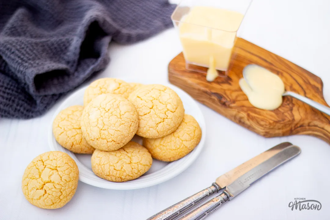 Custard and white chocolate biscuits on a white plate next to a pot of custard.
