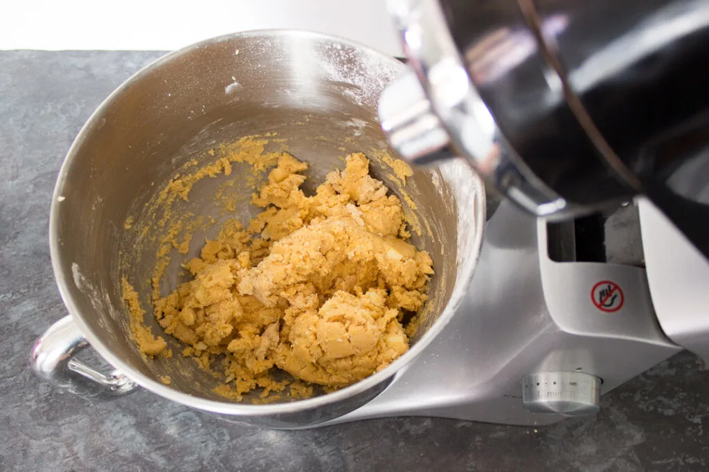 The finished custard and white chocolate biscuit dough in an electric stand mixer.
