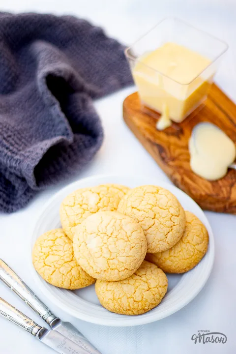 Custard and white chocolate biscuits on a plate with a small pot of custard and a teaspoon at the side.