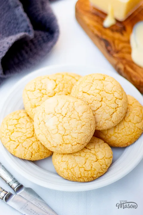 A plate of custard and white chocolate biscuits on a white table cloth.