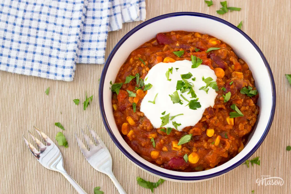 A bowl of chilli con carne topped with soured cream.