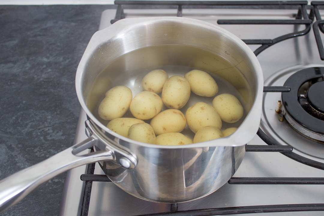 New potatoes in a saucepan of water on the stove.