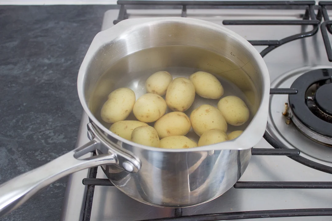 New potatoes in a saucepan of water on the stove.