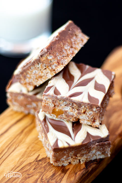 Five bars of Mars Bar Slice on a wooden board.