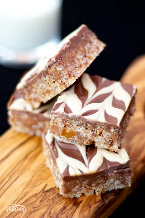 Five bars of Mars Bar Slice on a wooden board.