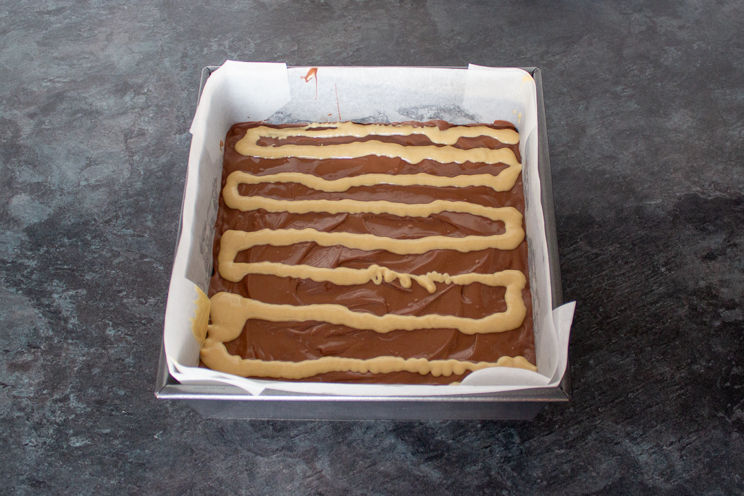 Melted blonde chocolate piped in lines on top of the milk chocolate topping.
