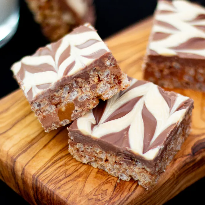 Two Mars Bar Slices on a wooden board.