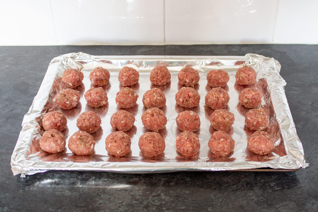Turkey meatballs on a foil lined baking tray.